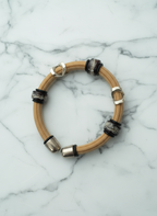 Bracelet with wooden band and metallic accents on a marble background